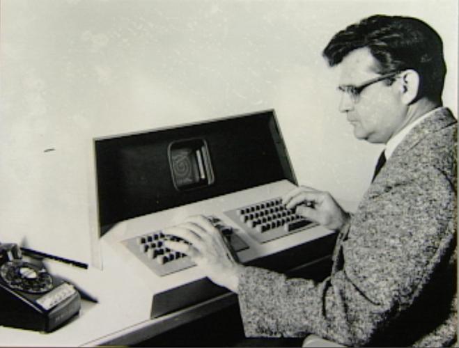 Glenn Culler sitting at an OLS terminal, looking at a very small screen and using a dual keyboard.